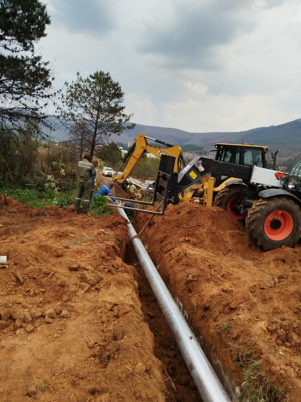 Wetpipe crew and plant installing slurry pipe in an open trench